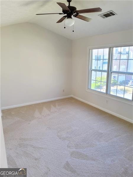 carpeted empty room featuring ceiling fan, baseboards, lofted ceiling, and visible vents