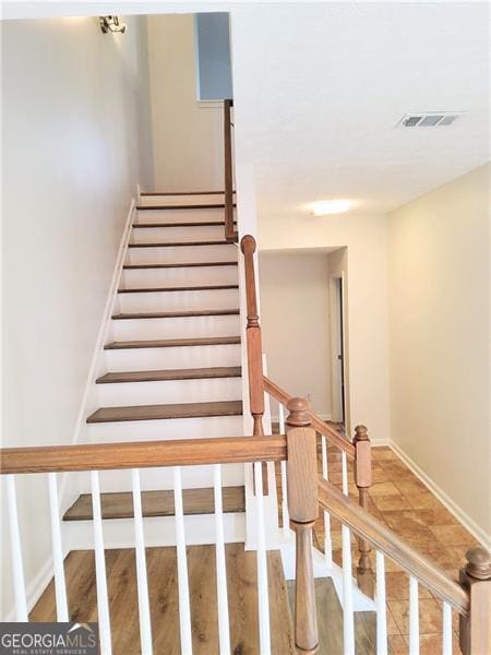 staircase featuring baseboards and visible vents