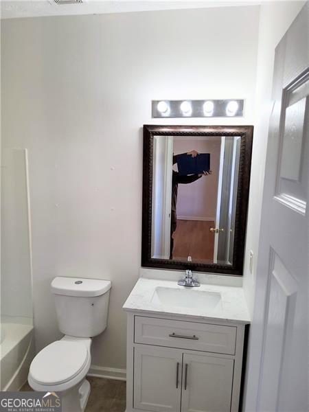 bathroom featuring toilet, vanity, and baseboards