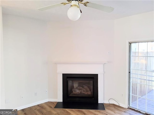 details with a fireplace with flush hearth, baseboards, a ceiling fan, and wood finished floors