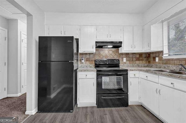 kitchen featuring white cabinets, dark wood-style floors, under cabinet range hood, black appliances, and decorative backsplash