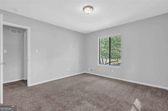 spare room featuring carpet flooring, baseboards, and visible vents