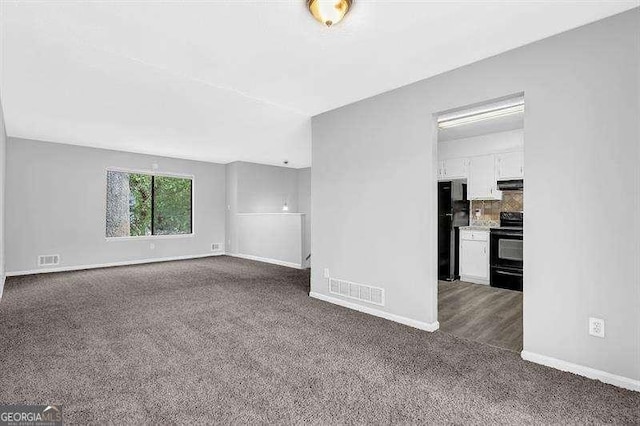 unfurnished living room with visible vents, baseboards, and dark colored carpet