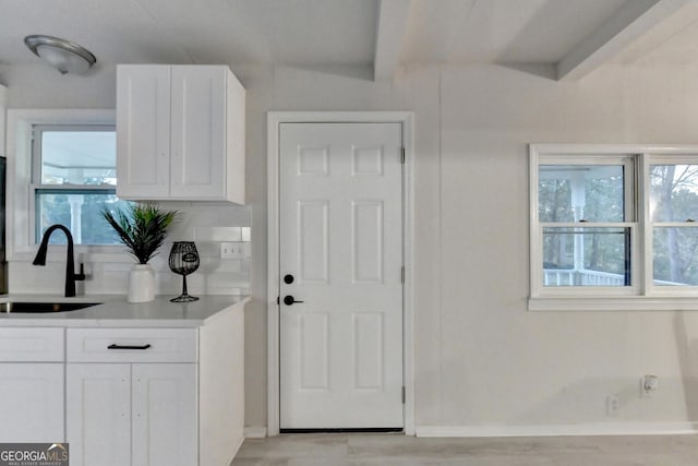 21 W Lake Dr, Oxford, GA 30054 - kitchen featuring white cabinets, light countertops, a sink, backsplash, and beam ceiling