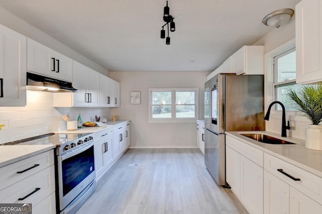 21 W Lake Dr, Oxford, GA 30054 - kitchen featuring a sink, appliances with stainless steel finishes, under cabinet range hood, white cabinetry, and backsplash