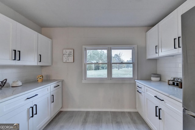 21 W Lake Dr, Oxford, GA 30054 - kitchen featuring light wood-style flooring, white cabinetry, light countertops, decorative backsplash, and baseboards