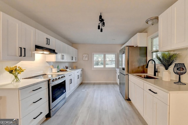 21 W Lake Dr, Oxford, GA 30054 - kitchen featuring backsplash, under cabinet range hood, appliances with stainless steel finishes, light wood finished floors, and a sink