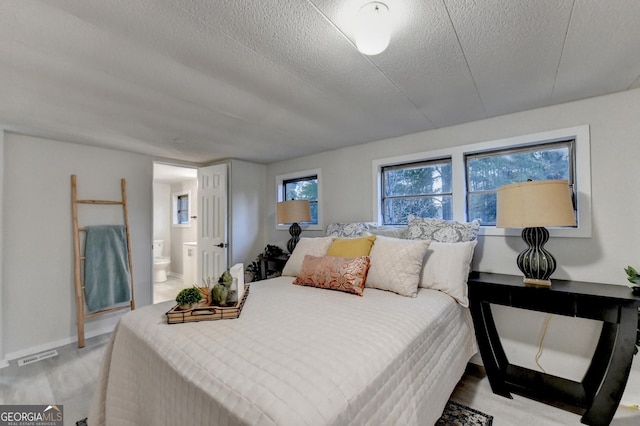 21 W Lake Dr, Oxford, GA 30054 - bedroom featuring connected bathroom, a textured ceiling, visible vents, wood finished floors, and baseboards