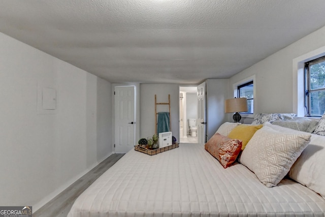 21 W Lake Dr, Oxford, GA 30054 - bedroom with connected bathroom, wood finished floors, and a textured ceiling
