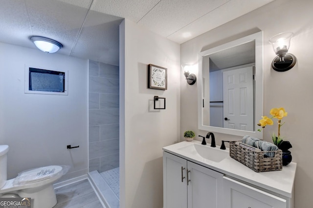 21 W Lake Dr, Oxford, GA 30054 - bathroom featuring a tile shower, a textured ceiling, vanity, and toilet