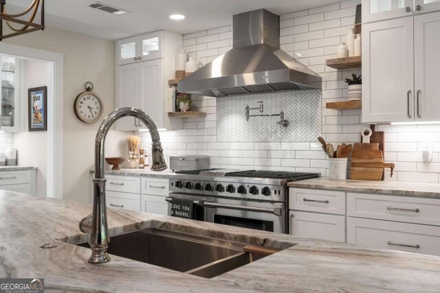 6477 Old Shadburn Ferry Rd, Buford, GA 30518 - kitchen featuring range hood, double oven range, white cabinets, light stone counters, and tasteful backsplash