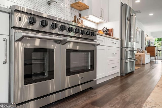 6477 Old Shadburn Ferry Rd, Buford, GA 30518 - kitchen with high quality appliances, decorative backsplash, recessed lighting, white cabinets, and dark wood-style flooring