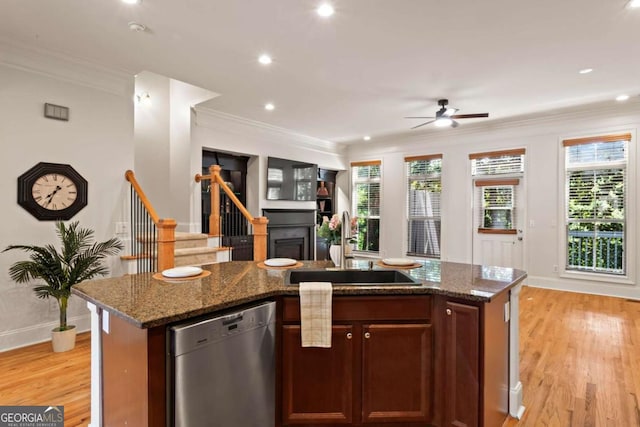 kitchen with a sink, ornamental molding, stainless steel dishwasher, and light wood-style flooring