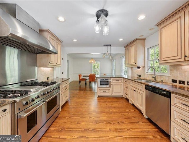 5761 Kentucky Downs Dr, Macon, GA 31210 - kitchen with appliances with stainless steel finishes, wall chimney range hood, light wood-type flooring, a peninsula, and backsplash