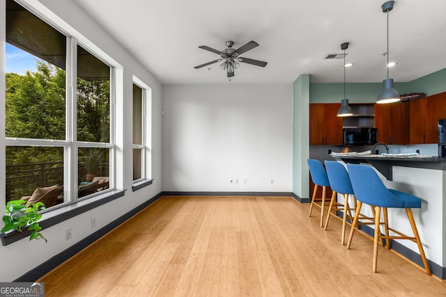 747 Ralph Mcgill Blvd NE Unit 223, Atlanta, GA 30312 - kitchen featuring black microwave, a kitchen breakfast bar, light wood finished floors, decorative light fixtures, and ceiling fan