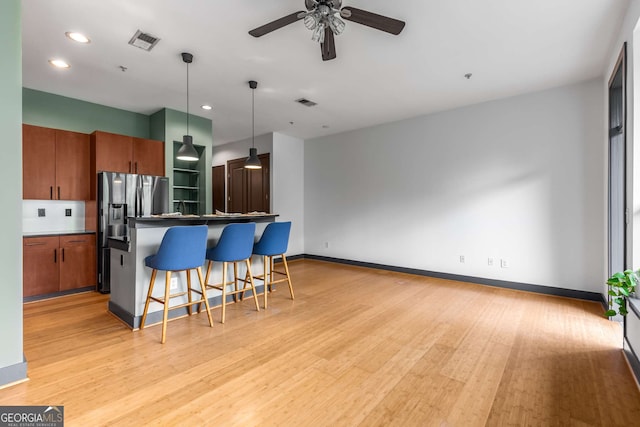 747 Ralph Mcgill Blvd NE Unit 223, Atlanta, GA 30312 - kitchen with stainless steel refrigerator with ice dispenser, brown cabinets, a kitchen breakfast bar, a ceiling fan, and light wood-type flooring