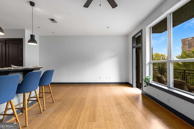 747 Ralph Mcgill Blvd NE Unit 223, Atlanta, GA 30312 - kitchen featuring light wood-style floors, a kitchen breakfast bar, a ceiling fan, baseboards, and pendant lighting