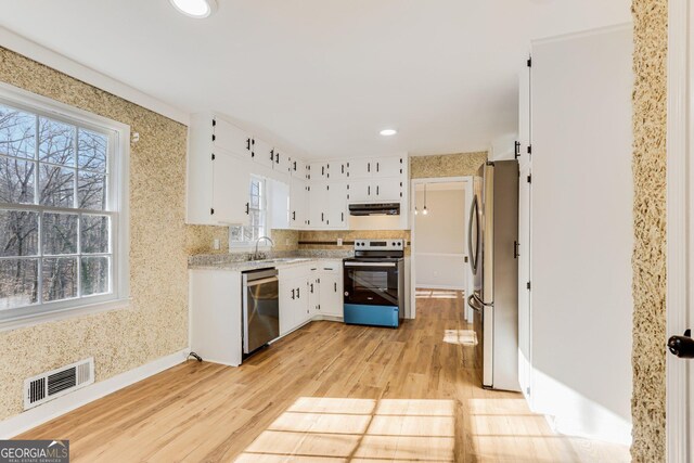 5465 N Fork Dr SW, Lilburn, GA 30047 - kitchen with light wood-style floors, wallpapered walls, visible vents, appliances with stainless steel finishes, and extractor fan