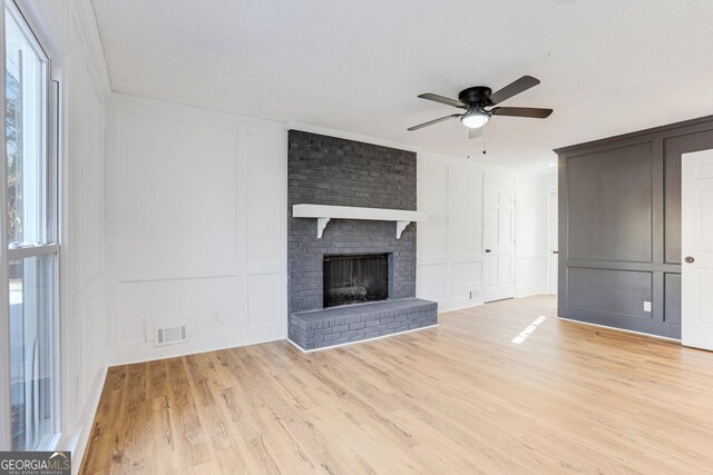 5465 N Fork Dr SW, Lilburn, GA 30047 - unfurnished living room featuring visible vents, a decorative wall, ceiling fan, a wealth of natural light, and light wood-style floors