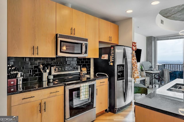 kitchen with stainless steel appliances, light wood-style floors, light brown cabinets, and decorative backsplash