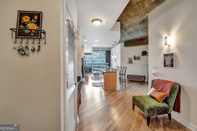 hall with floor to ceiling windows, light wood-style flooring, and baseboards