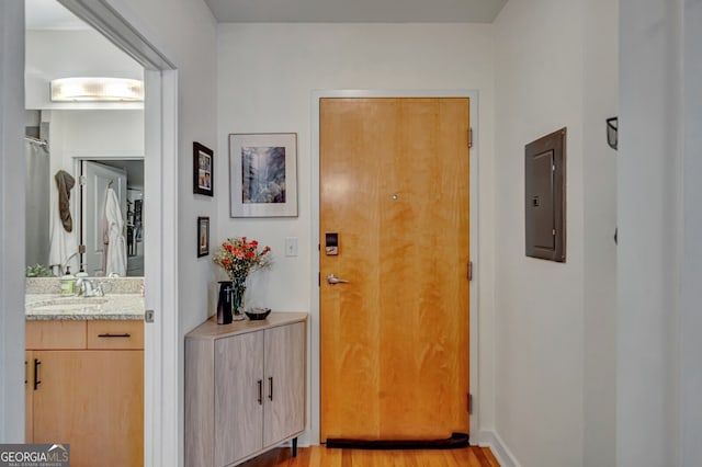 entryway featuring electric panel, light wood-type flooring, and a sink