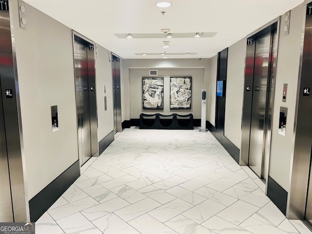 corridor featuring elevator and marble finish floor