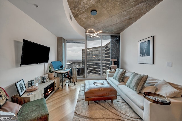 living area featuring wood finished floors, floor to ceiling windows, visible vents, and a notable chandelier