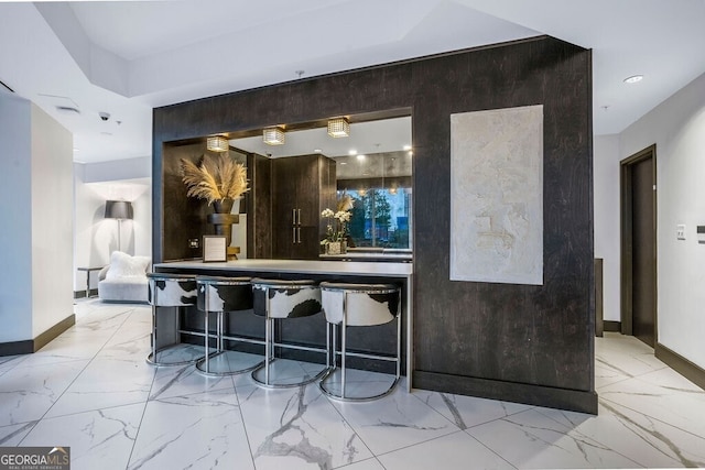 bar with recessed lighting, marble finish floor, and baseboards