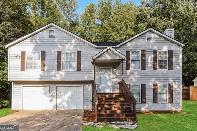 split foyer home with a garage, a chimney, fence, a front lawn, and driveway
