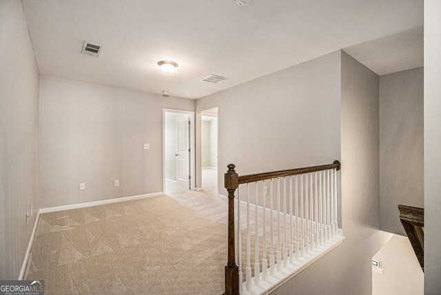 unfurnished bedroom featuring baseboards, light carpet, ensuite bath, visible vents, and a tray ceiling