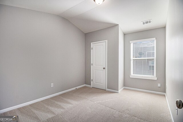 empty room featuring carpet, visible vents, baseboards, and lofted ceiling