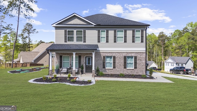 view of front of property with a porch, a front yard, a shingled roof, and brick siding