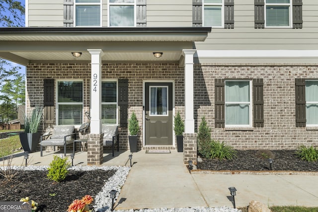 property entrance featuring covered porch and brick siding