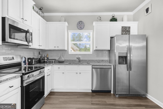 kitchen featuring white cabinetry, ornamental molding, appliances with stainless steel finishes, and a sink