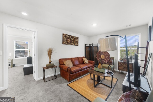 carpeted living room with visible vents, baseboards, and a healthy amount of sunlight