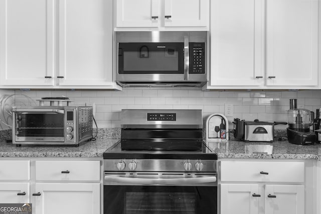 kitchen featuring a toaster, white cabinetry, stainless steel appliances, and tasteful backsplash
