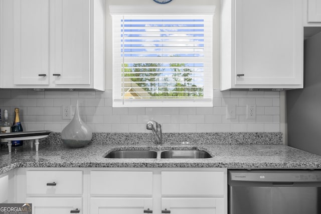 kitchen with a sink, tasteful backsplash, light stone counters, white cabinetry, and stainless steel dishwasher
