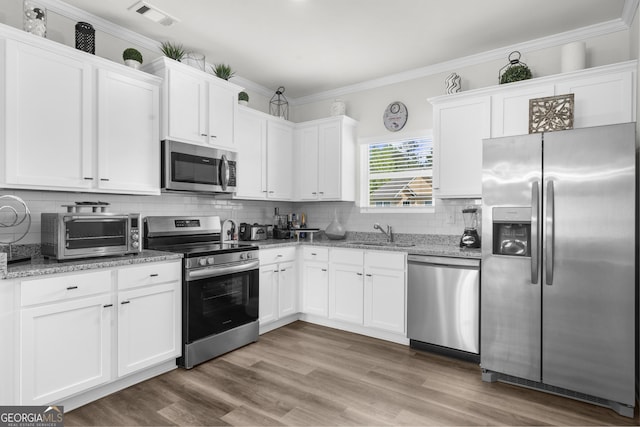 kitchen featuring a toaster, stainless steel appliances, a sink, white cabinetry, and visible vents