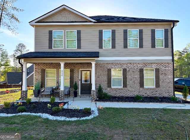 view of front of house featuring covered porch, brick siding, and a front lawn