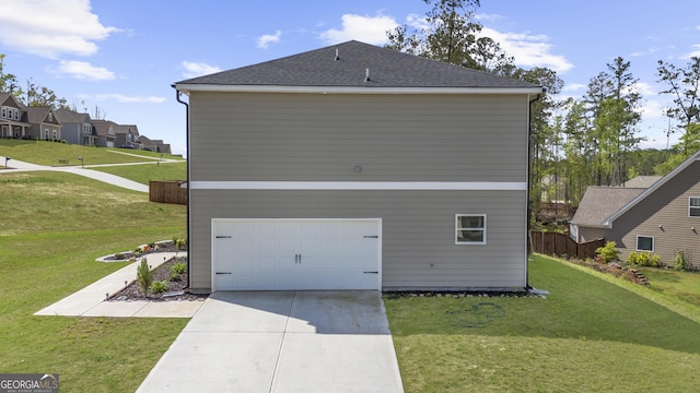 view of side of property featuring concrete driveway, a yard, a garage, and a shingled roof