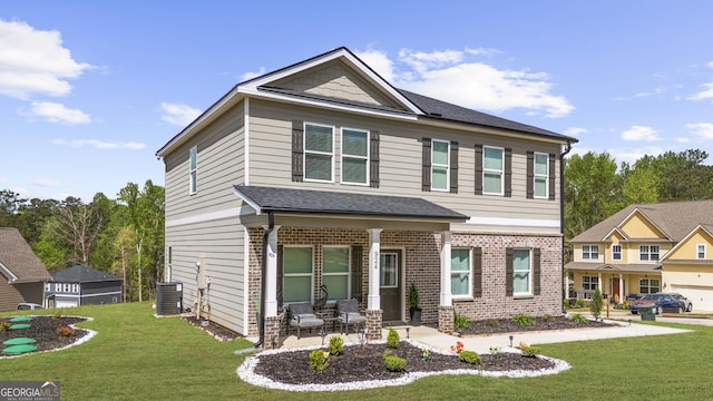 craftsman inspired home featuring brick siding, a front lawn, cooling unit, and roof with shingles