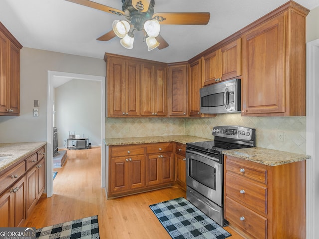75 The Farm Rd, Mcdonough, GA 30252 - kitchen with stainless steel appliances, a ceiling fan, light wood-style floors, decorative backsplash, and brown cabinets