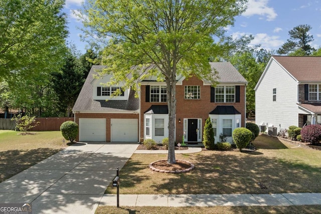 colonial home with central AC unit, a garage, fence, brick siding, and driveway