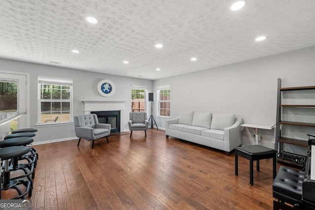 living area featuring hardwood / wood-style floors, baseboards, a glass covered fireplace, and plenty of natural light