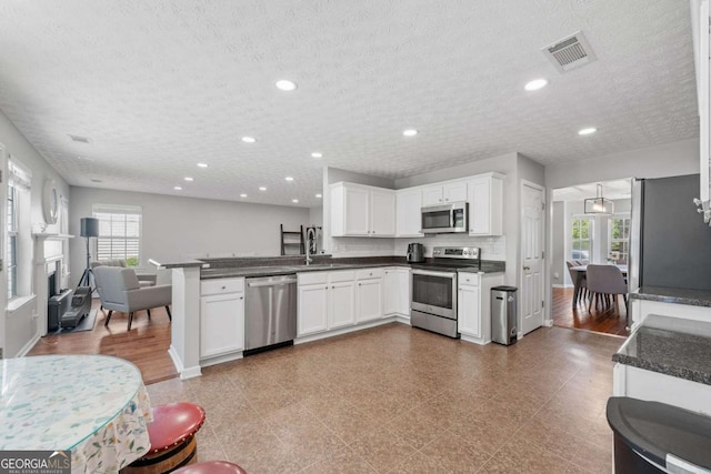 kitchen with dark countertops, visible vents, appliances with stainless steel finishes, and a peninsula