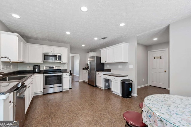 kitchen with a sink, baseboards, dark countertops, and stainless steel appliances