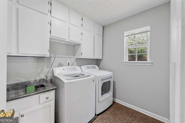 laundry area with independent washer and dryer, a textured ceiling, baseboards, and cabinet space