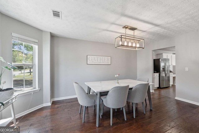 dining room featuring visible vents, baseboards, a textured ceiling, and dark wood finished floors