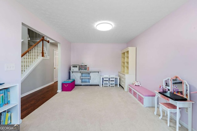 rec room with a textured ceiling, carpet flooring, and baseboards